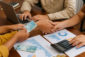 Investidores e empreendedores negociando com gráficos e reais sobre a mesa, representando empréstimos coletivos no Brasil.