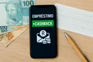 Smartphone sobre mesa com dinheiro e documentos bancários, simbolizando Empréstimos com cashback e o uso de aplicativos financeiros que oferecem recompensas ao consumidor.